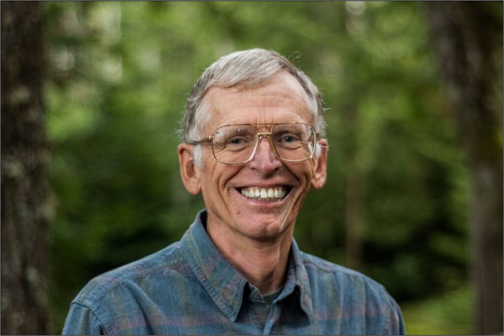 Don Endicott smiling in front of a green outdoor background
